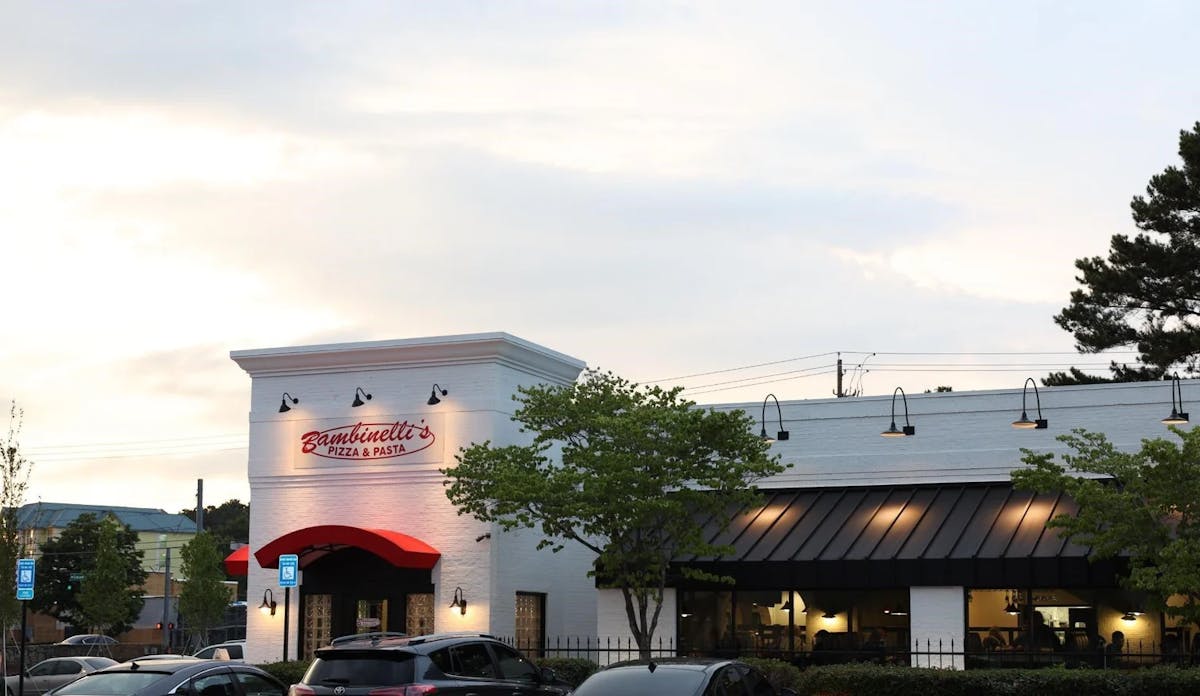 A restaurant exterior with several cars parked in front, showcasing a busy dining area