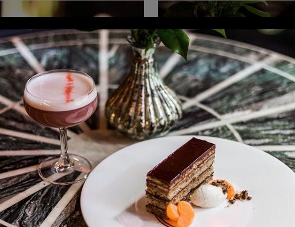 a piece of cake on a plate with a cocktail