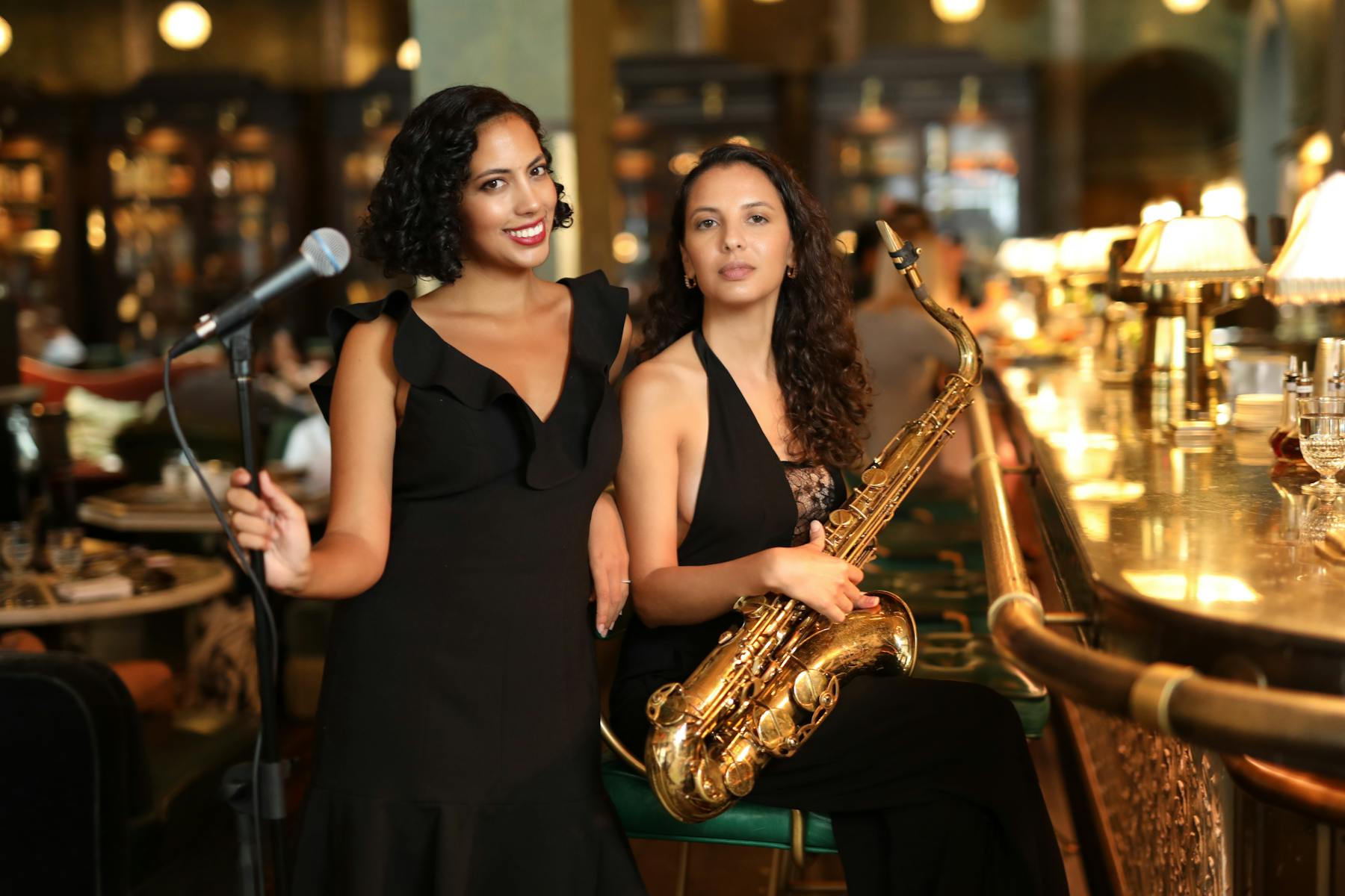 Two woman at the bar, one with a microphone, one with a Saxaphone
