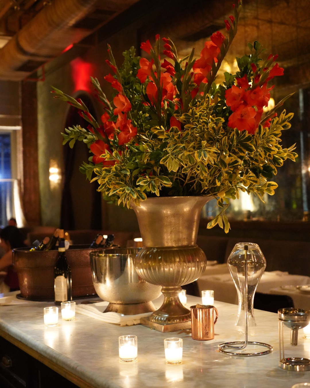 a vase of flowers on a table with wine glasses