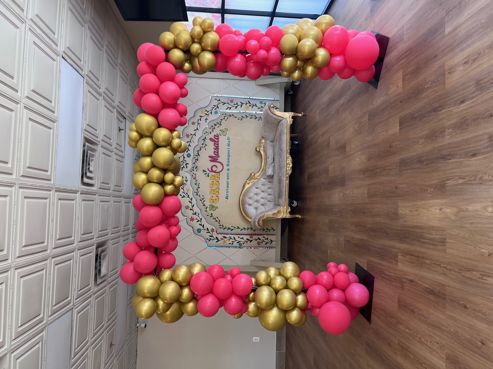 a pink and gold balloon arch decor in banquet hall entrance