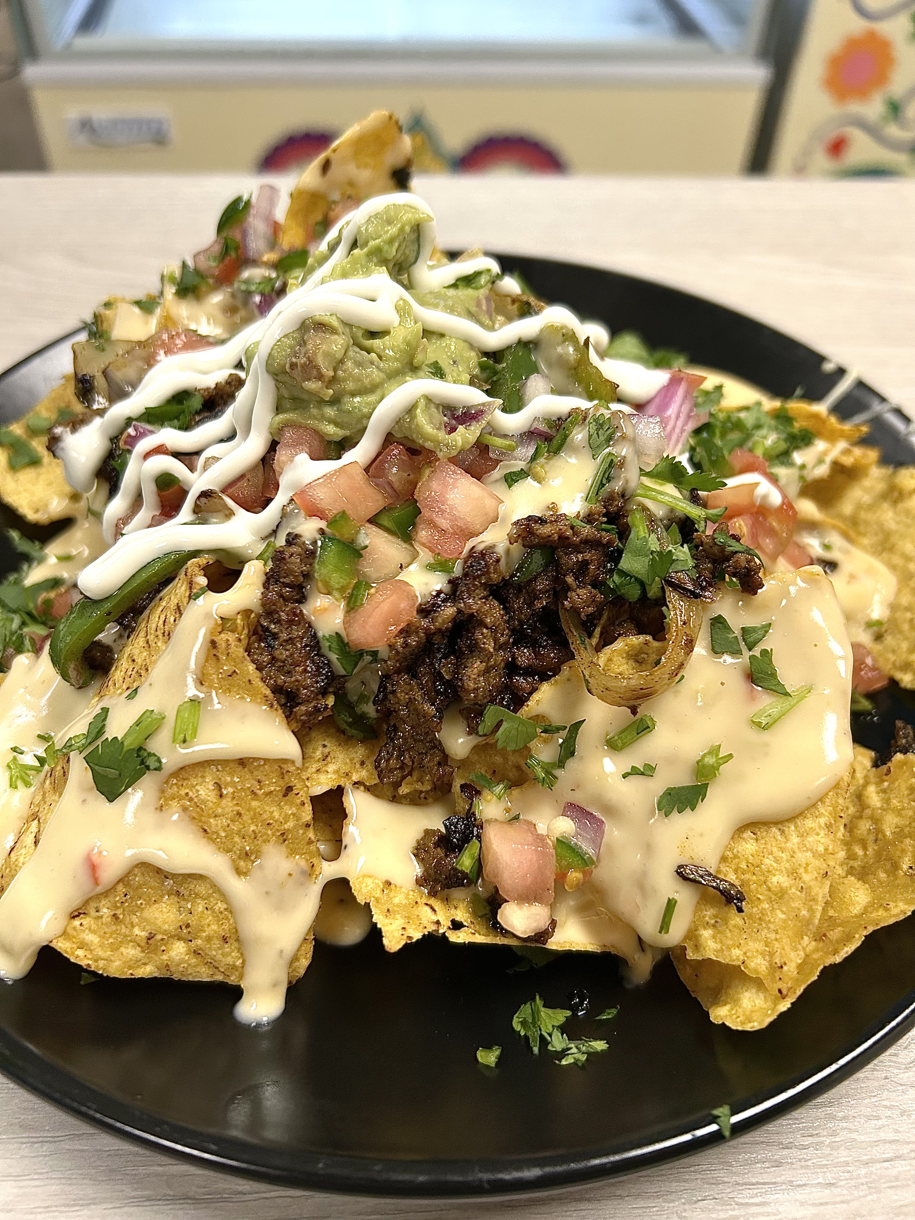 a plate of seasoned ground beef nachos with pico de gallo, queso , creama etc