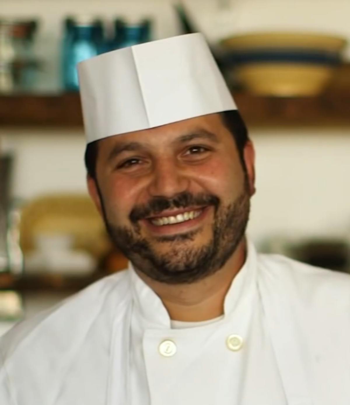 a man wearing a hat and smiling at the camera