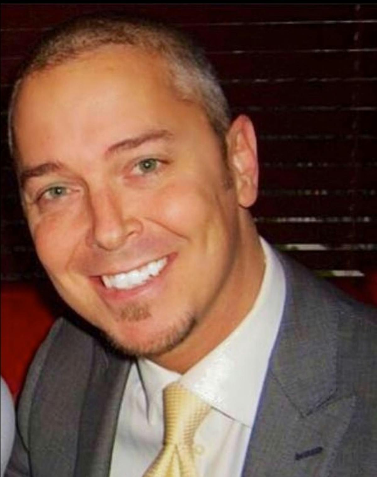 a man wearing a suit and tie smiling at the camera