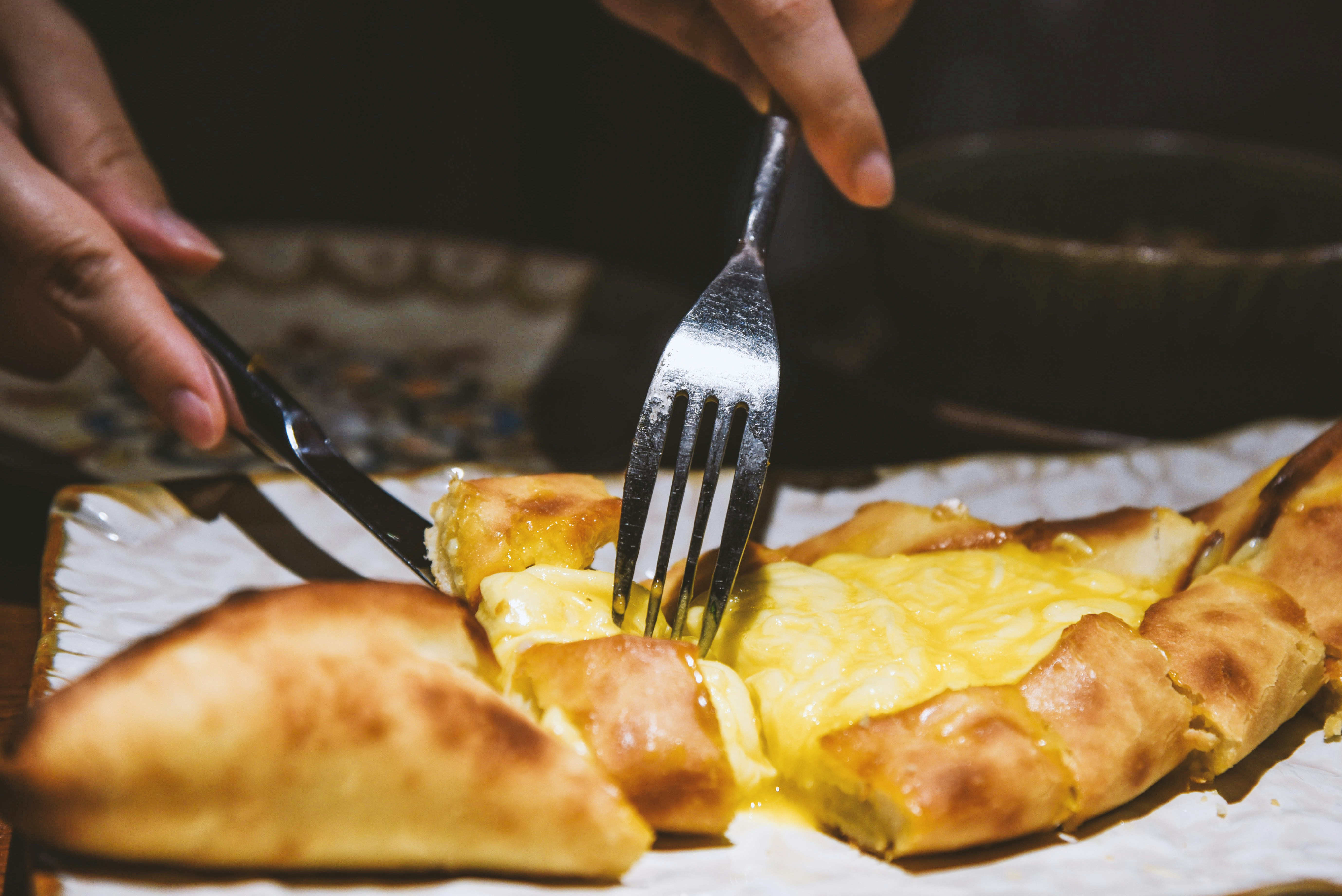 a close up of a person cutting a piece of pizza