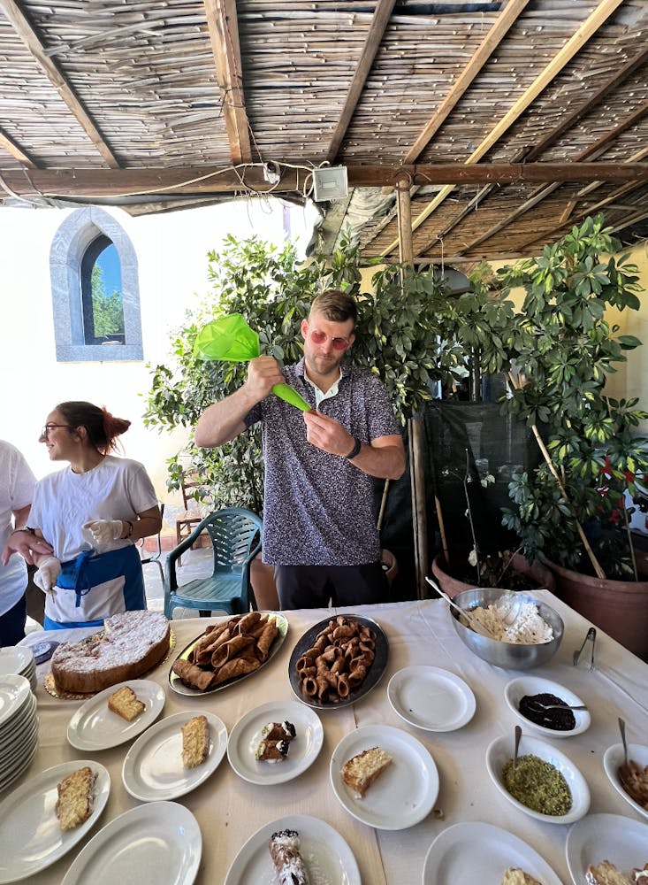 a group of people standing around a table with a plate of food