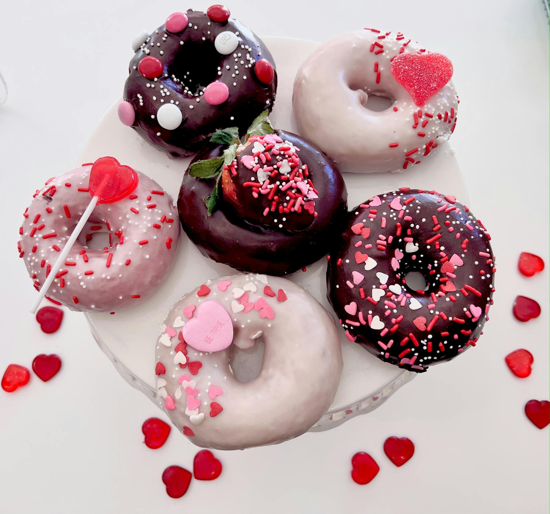 a pink plate topped with different types of doughnuts on a table