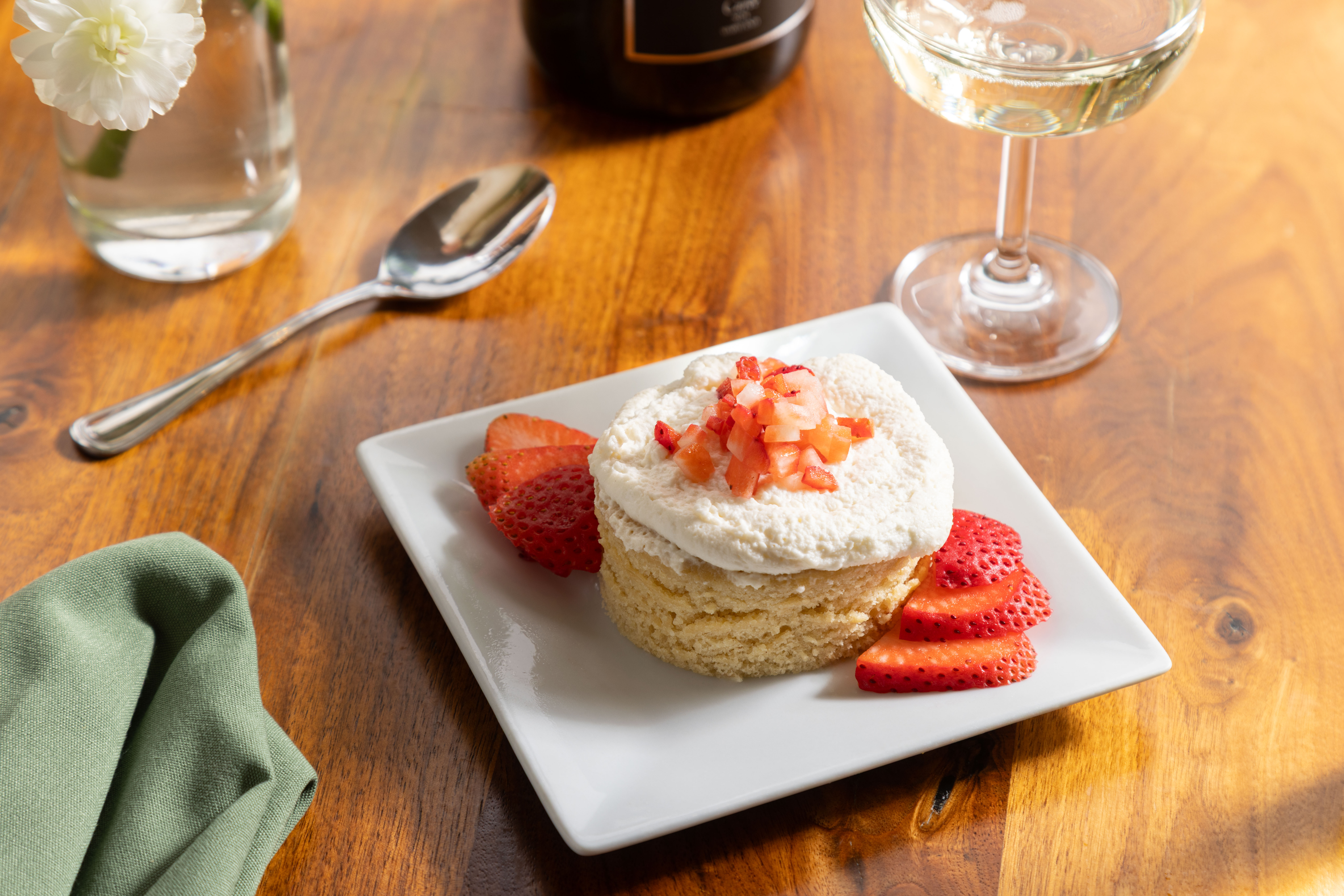 a piece of cake on a plate next to a glass of wine