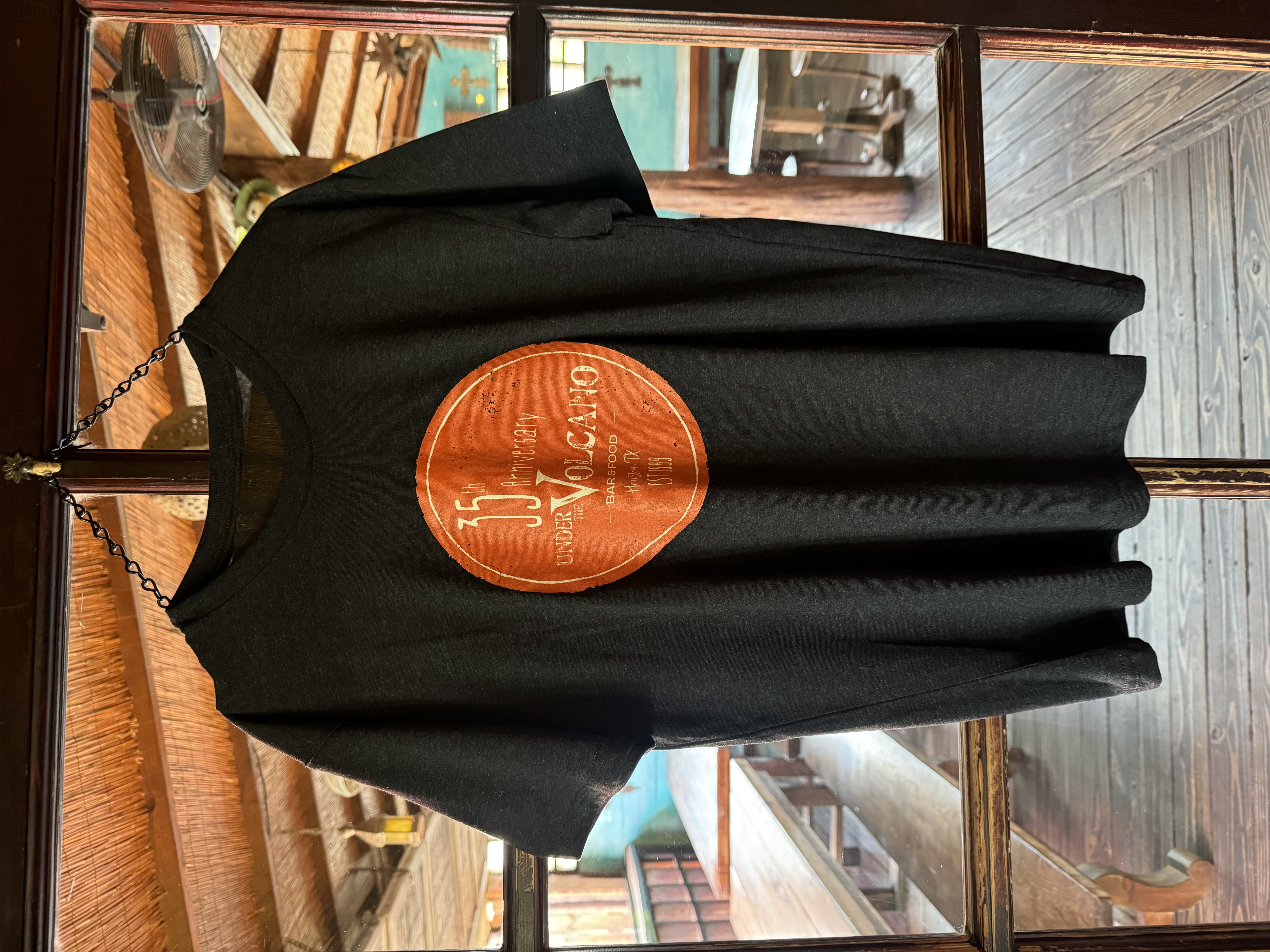 Black t-shirt with a round logo saying 35 Anniversary Under the Volcano