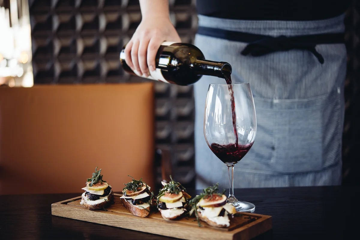 a person pouring wine into a glass