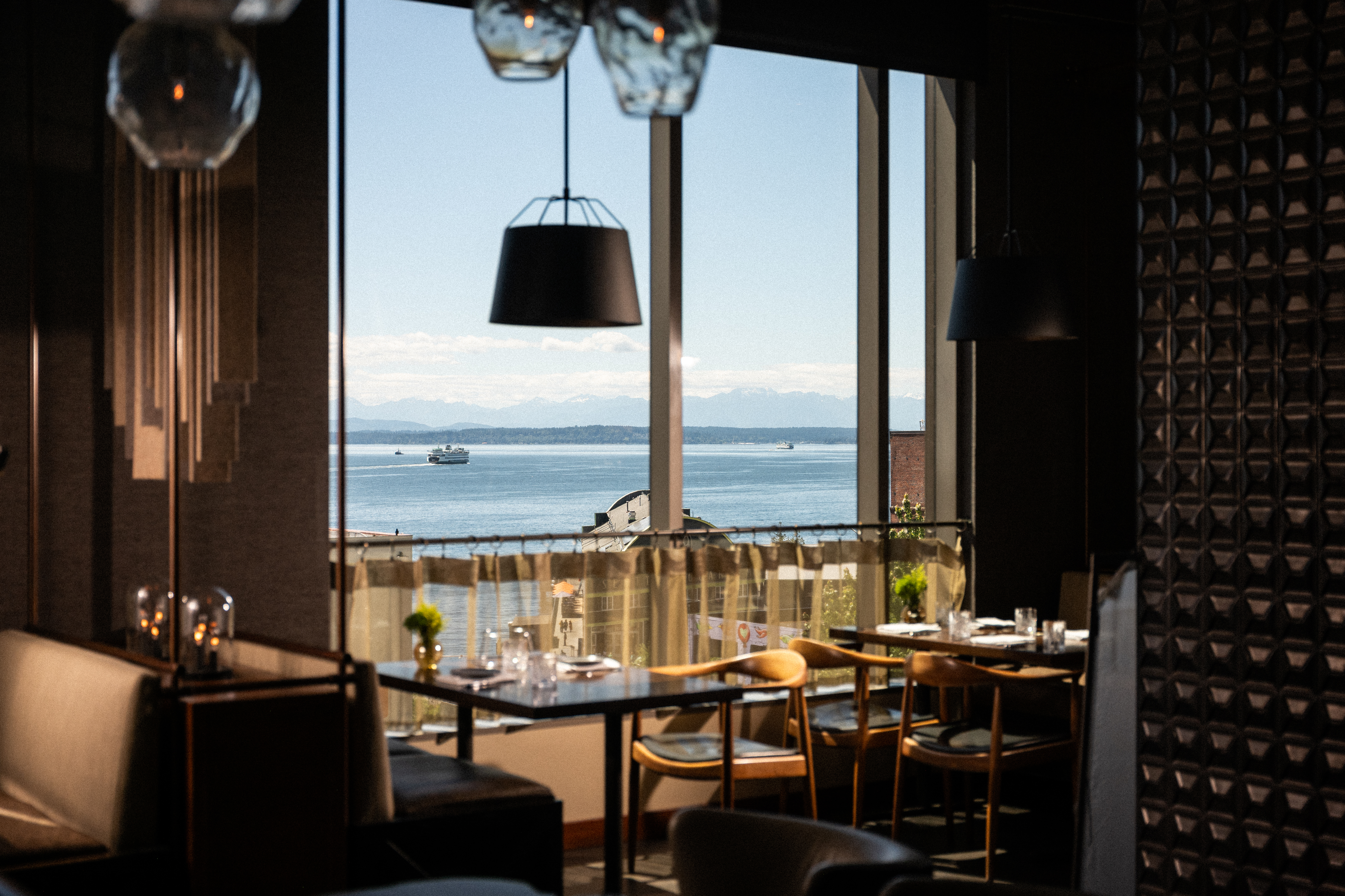 a room with tables and chairs and a view of the water