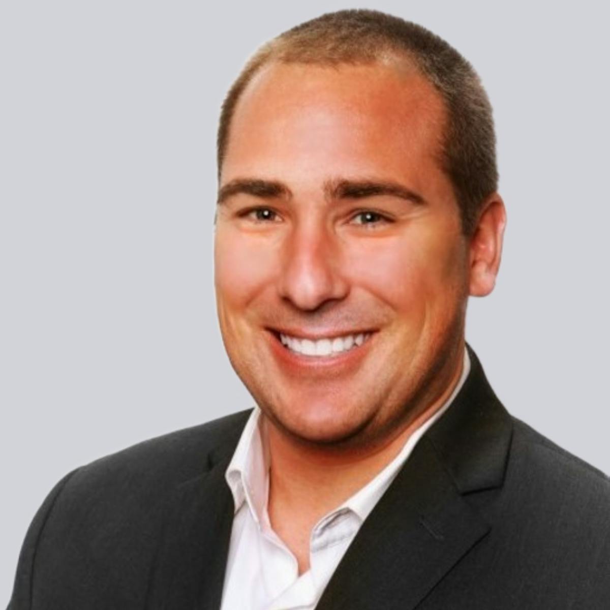 a man wearing a suit and tie smiling at the camera