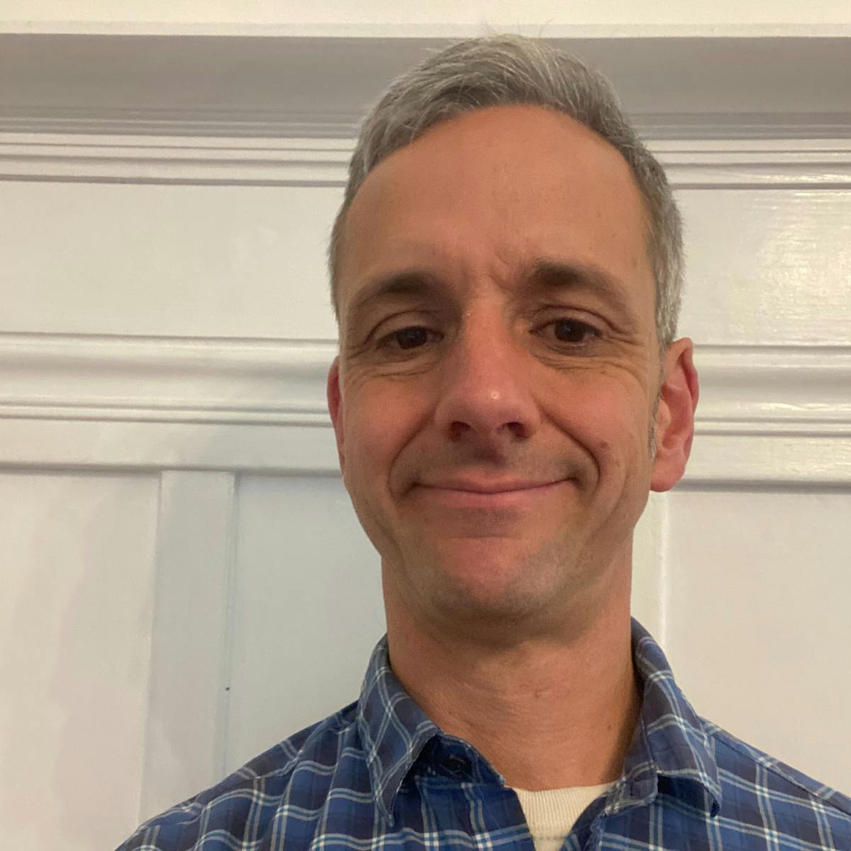 a man wearing a blue shirt and smiling at the camera