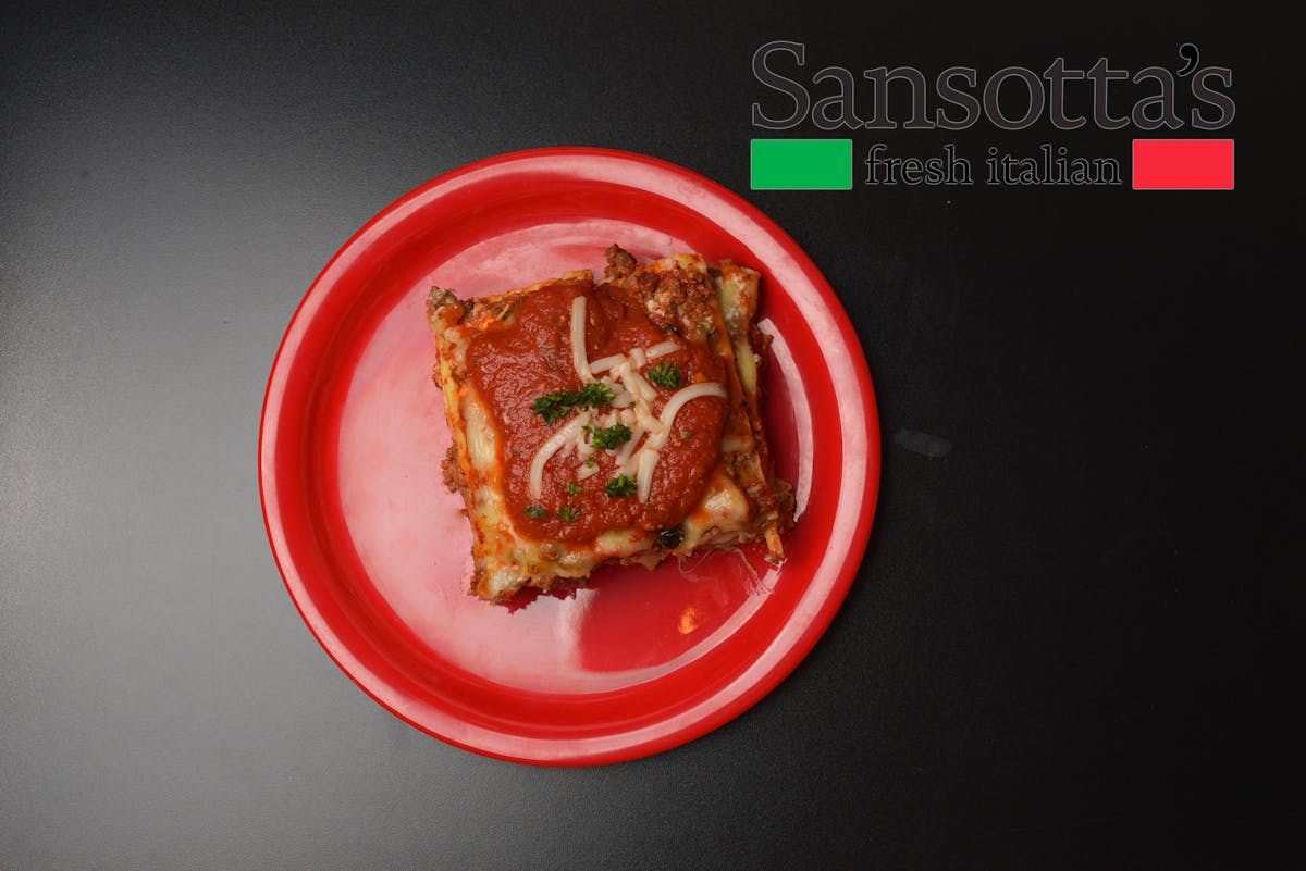 a red plate topped with a piece of lasagna