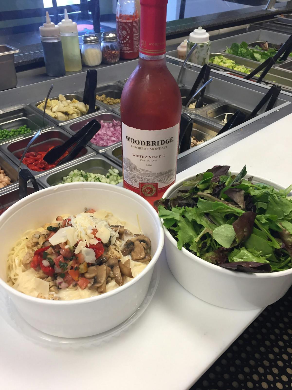 a bowl of salad and a bottle of wine