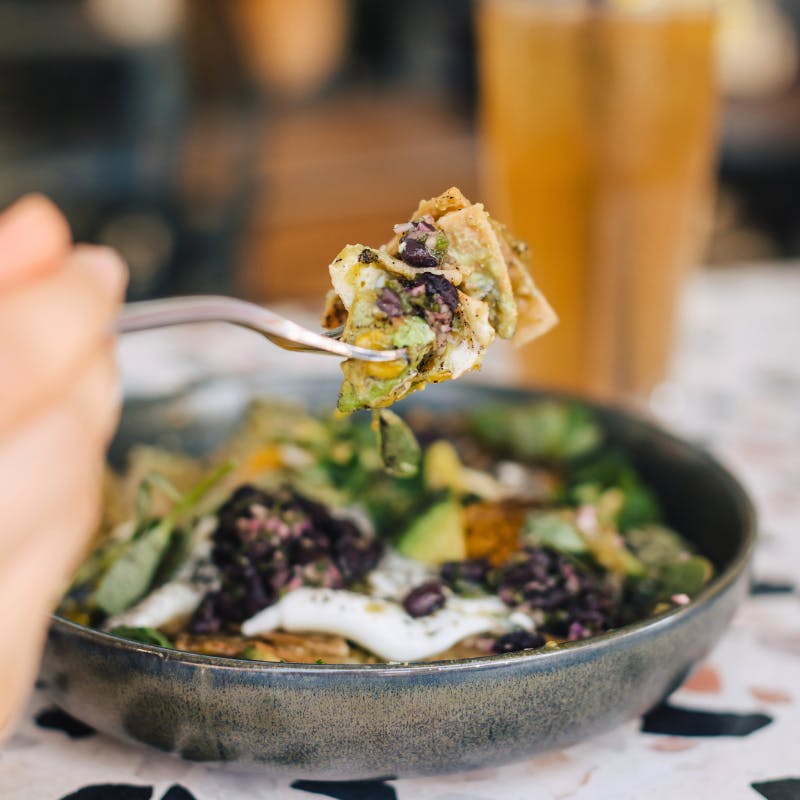 Close-up of chilaquiles with black beans, avocado, and crema — a flavorful and hearty breakfast in Newport Beach.