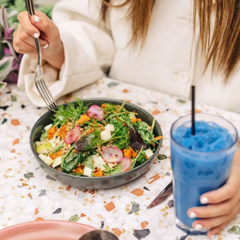 a woman holding a plate of food on a table