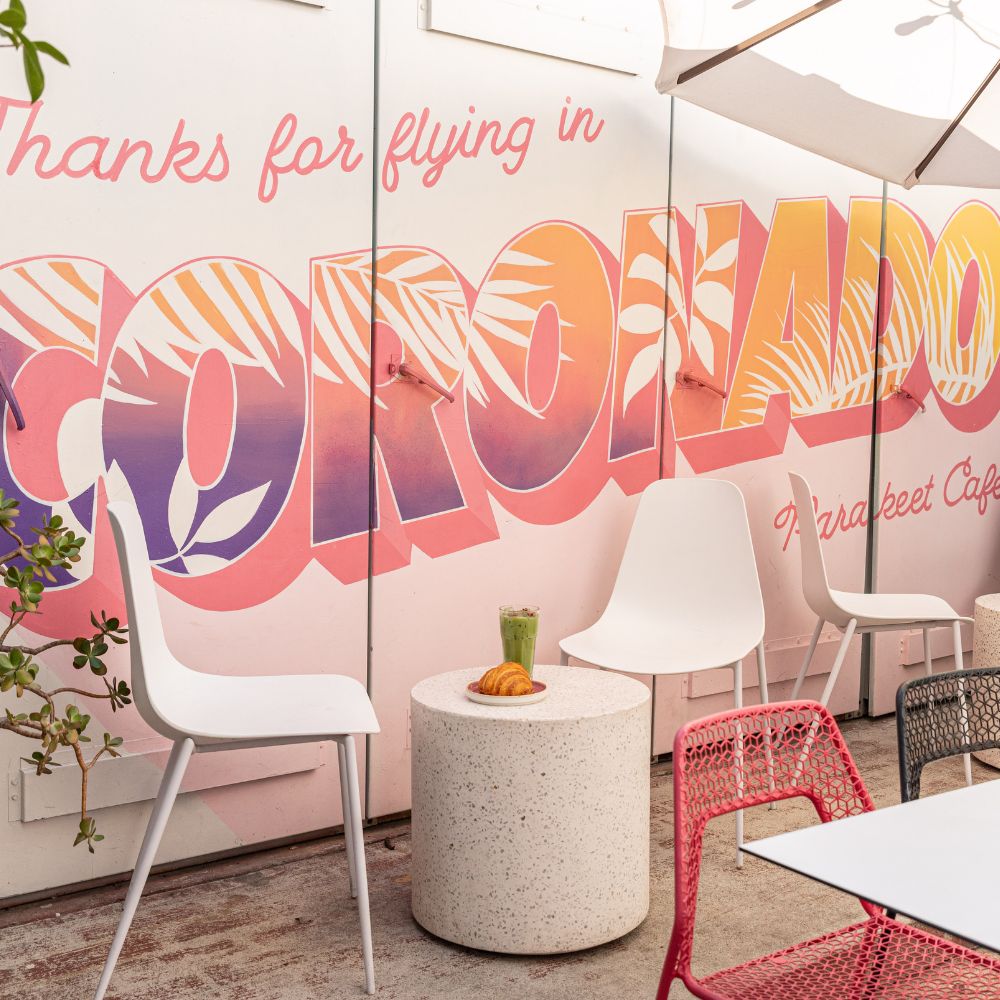 Outdoor seating area at Parakeet Café in Coronado with a croissant and green juice on the table — a relaxed spot for breakfast in Coronado.