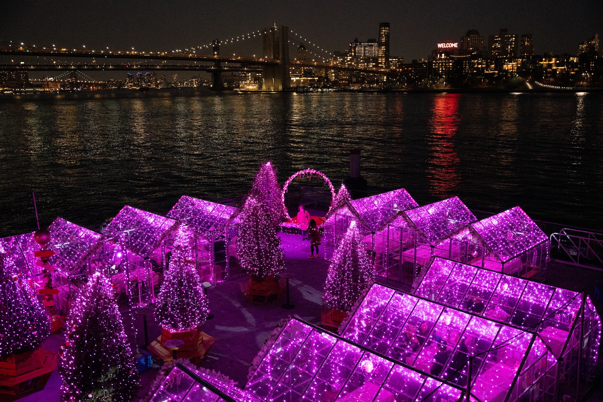 Pink Pier exterior on the waterfront with the Brooklyn Bridge in the background.