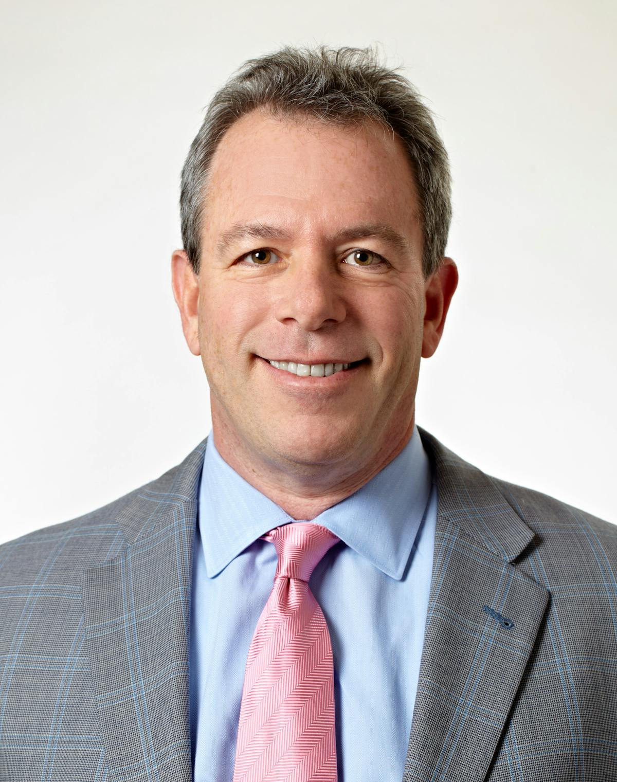 a man wearing a suit and tie smiling at the camera