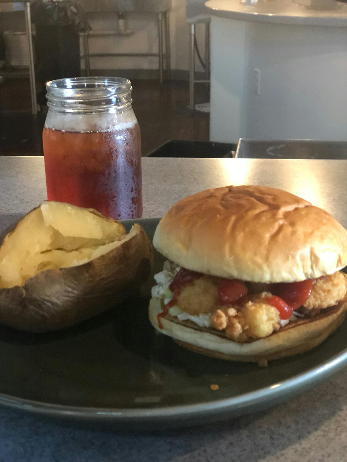 a pan topped with a burger, potato chips and a cup of iced tea
