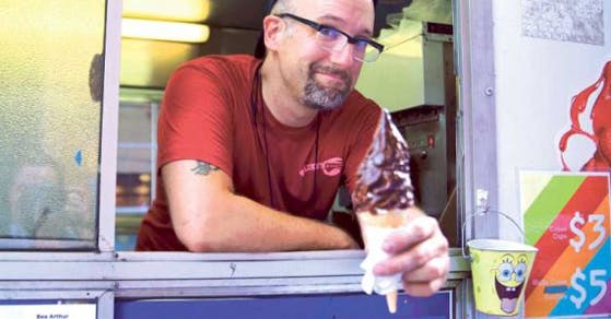 a man holding a chocolate ice cream on a food truck