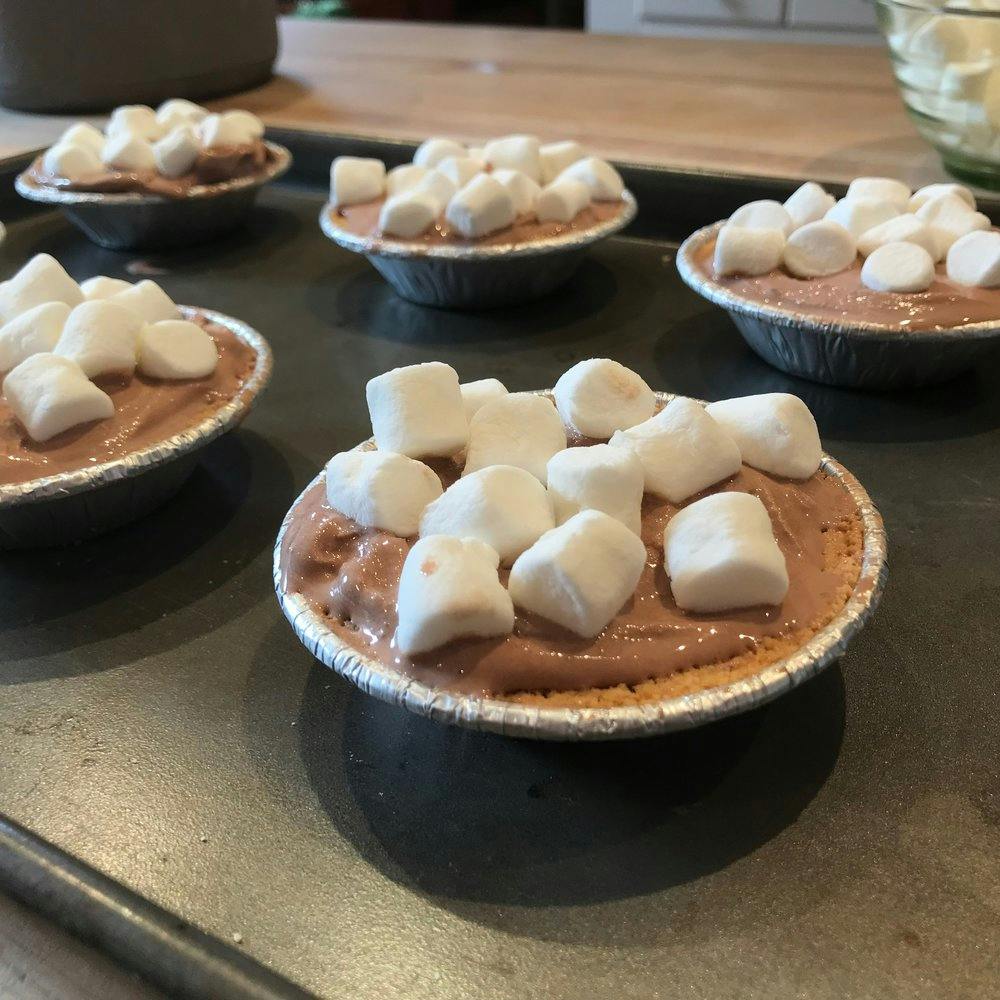 a tray with chocalte cups topped with marshmallows