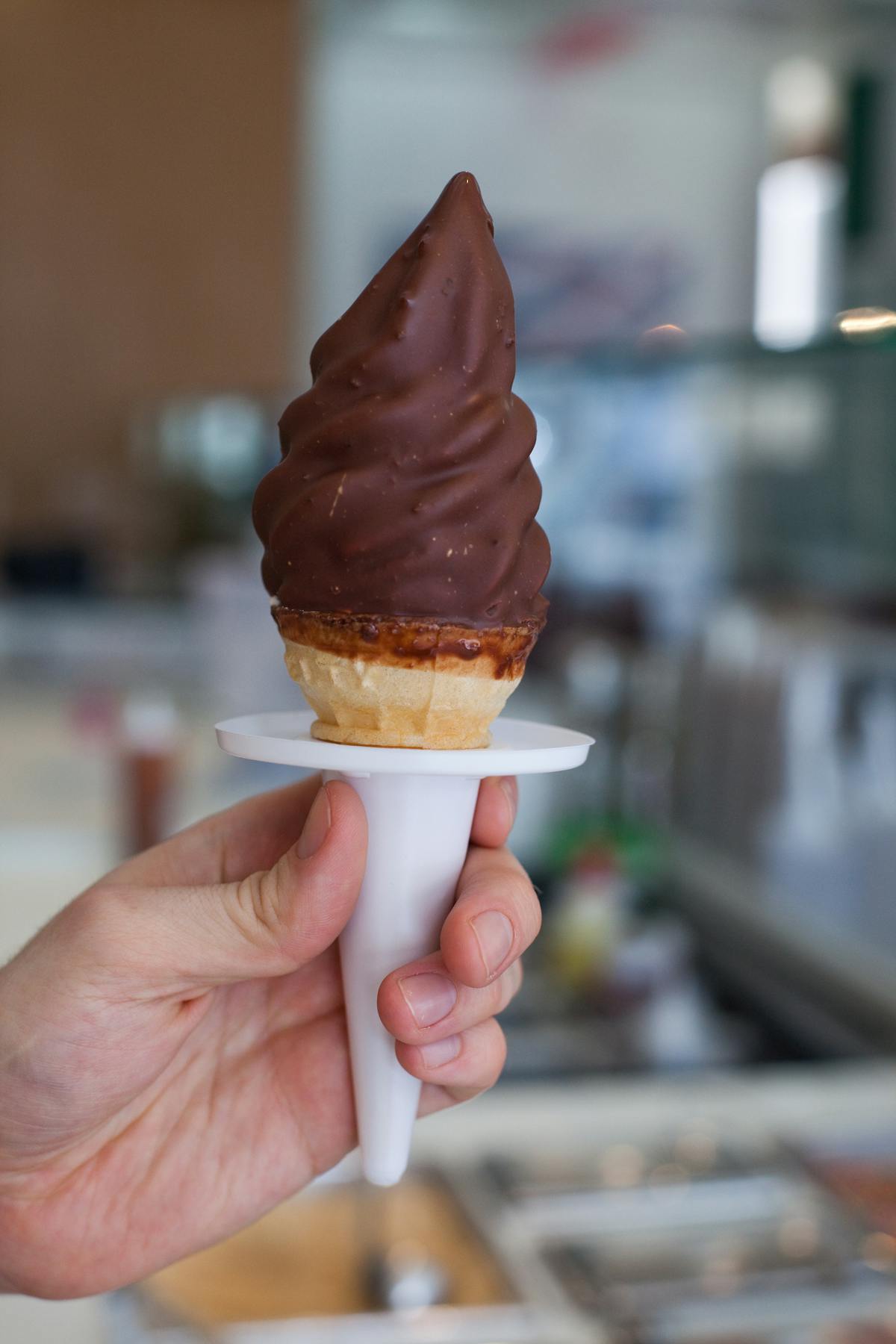 a hand holding a chocolate ice cream