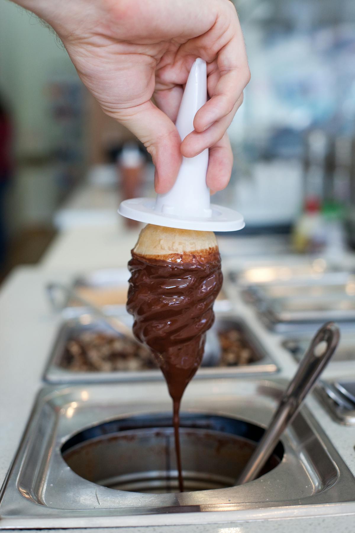 an ice cream being dipped in chocolate syrup