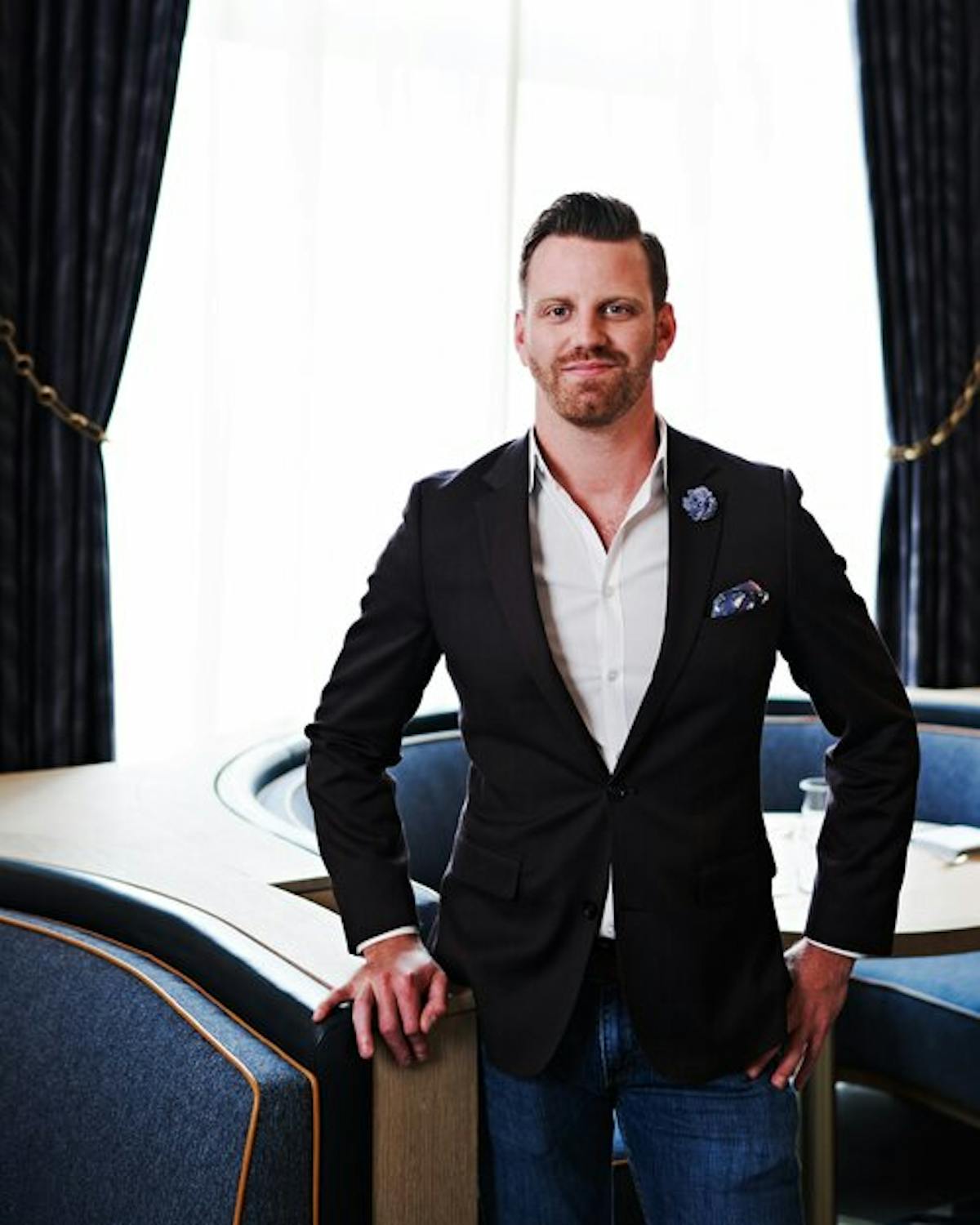 a man in a suit standing in front of a curtain