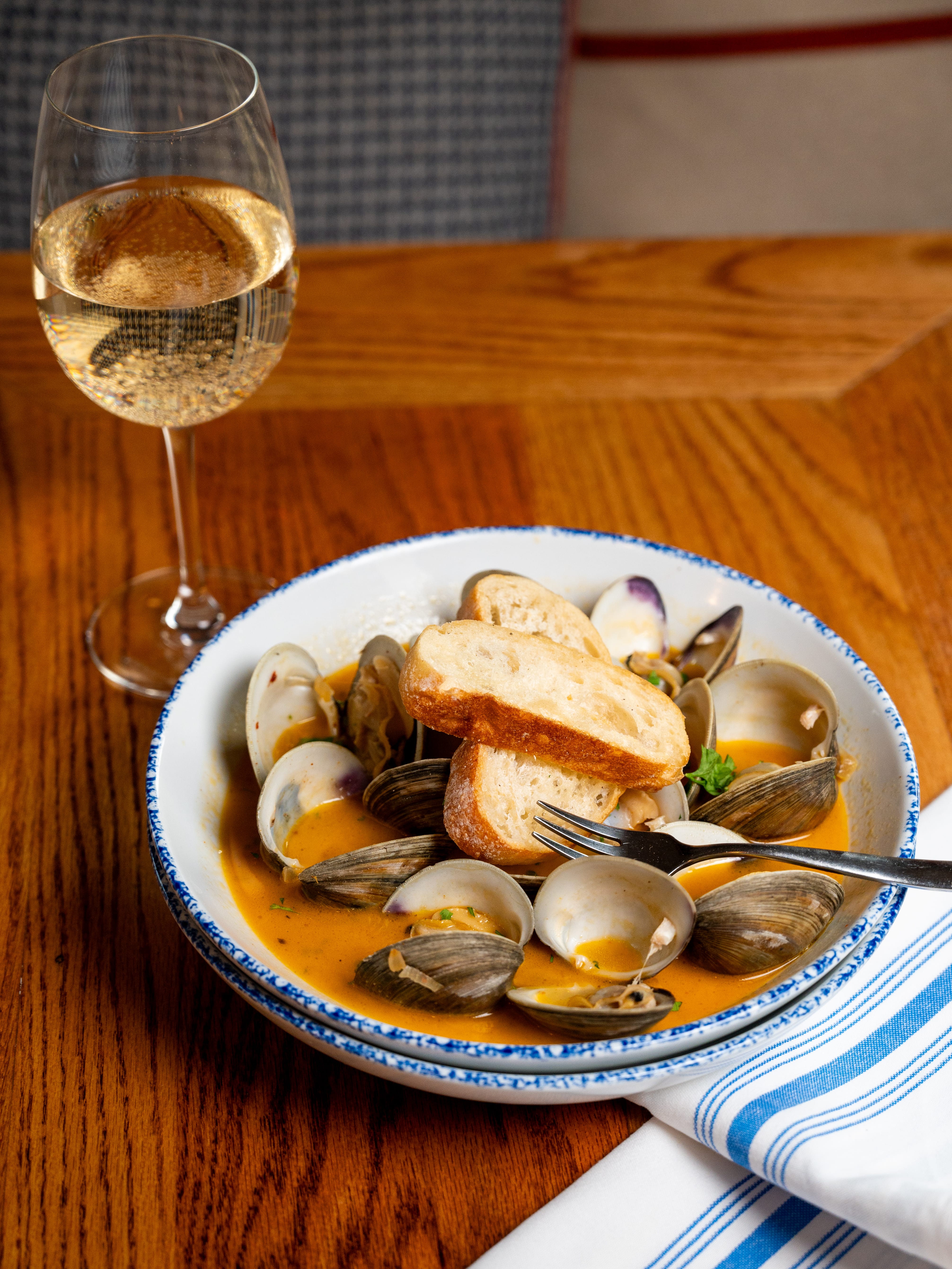 a bowl of clams and a glass of wine