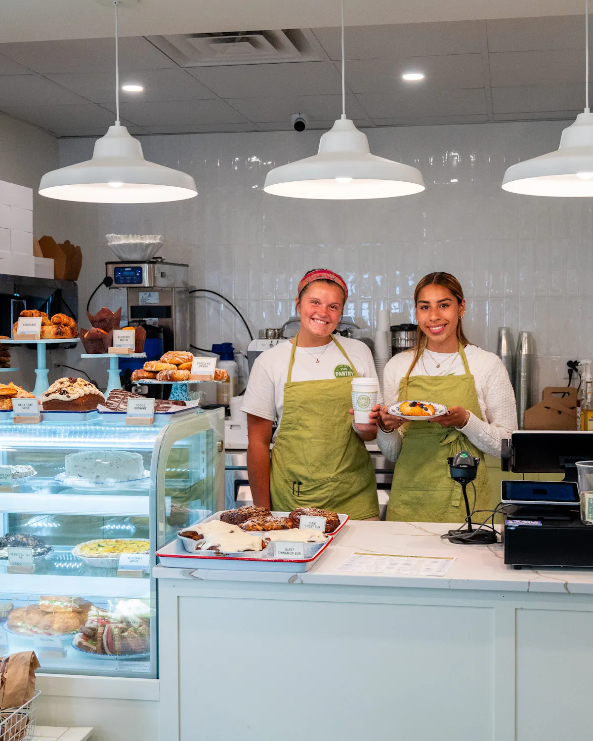 two women standing behind a counter with food