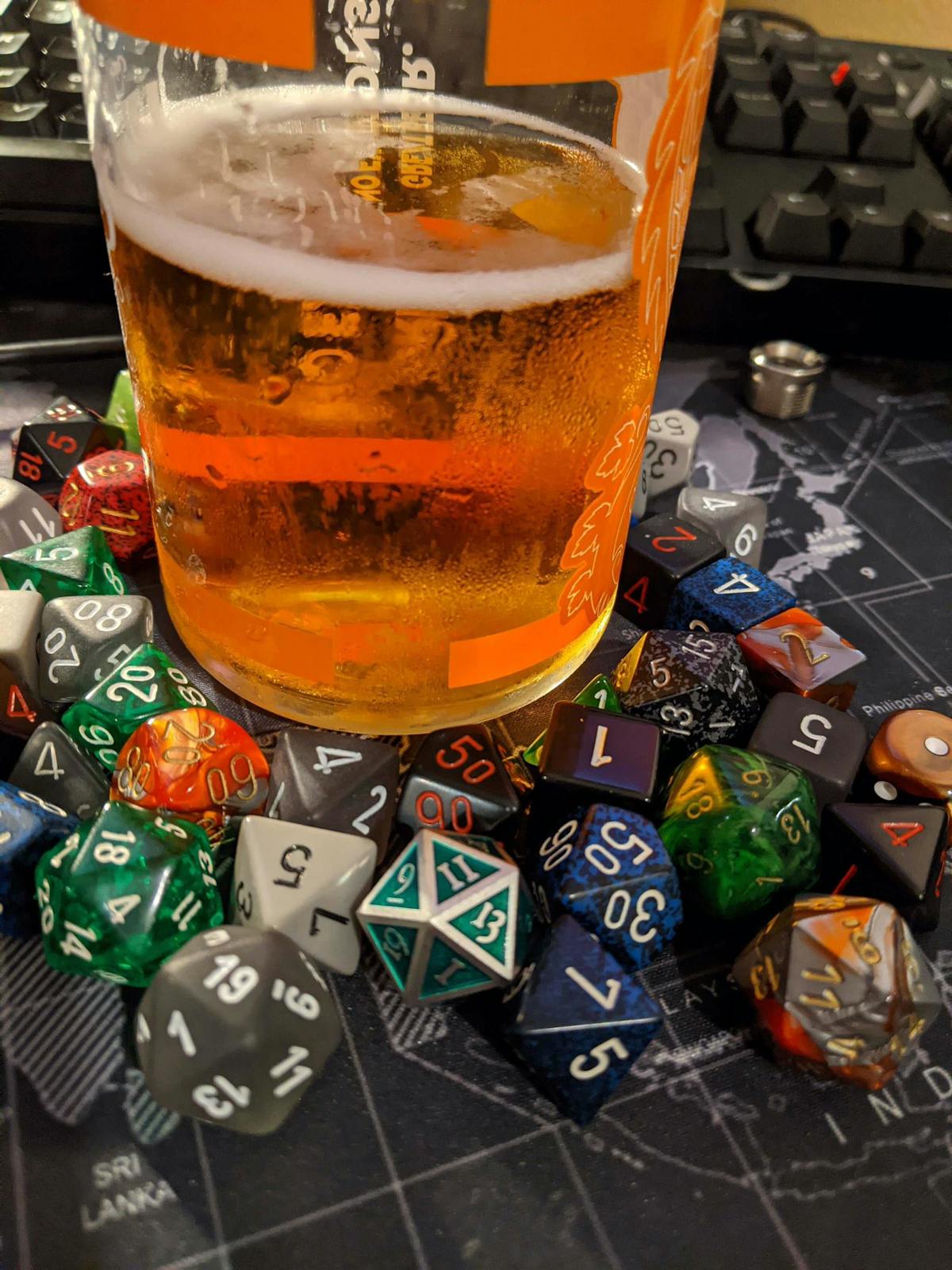 a glass of beer surrounded by tabletop roleplaying game di on a table