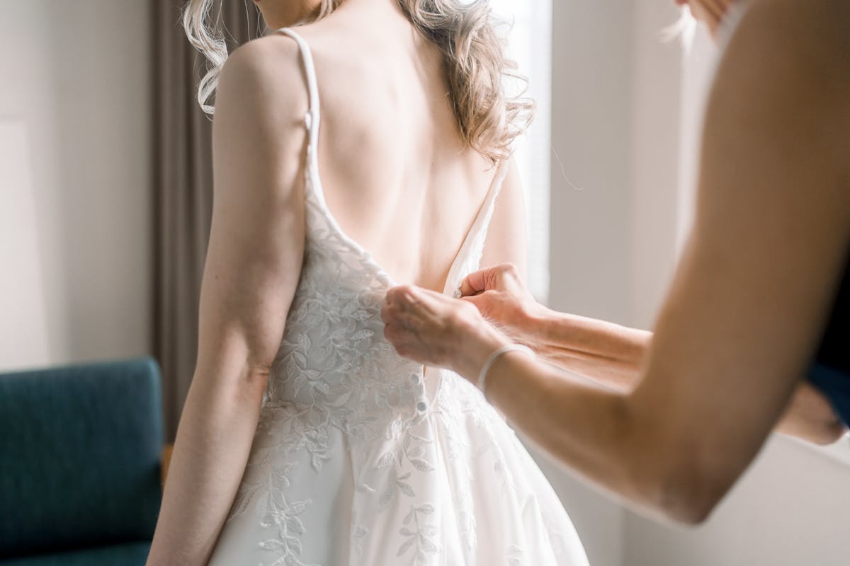 Bride getting wedding dress buttoned up