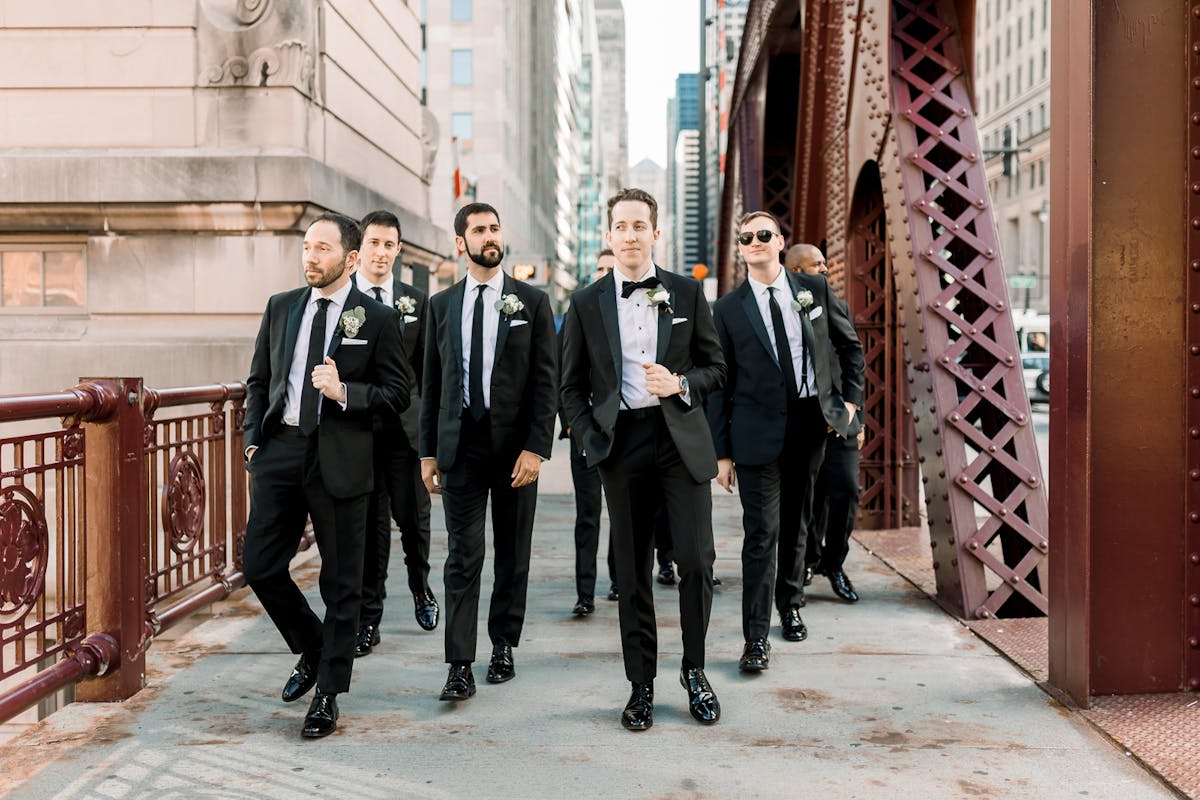 Grooms men walking across downtown chicago bridge