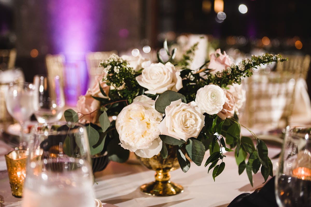 a vase of flowers on a table with wine glasses
