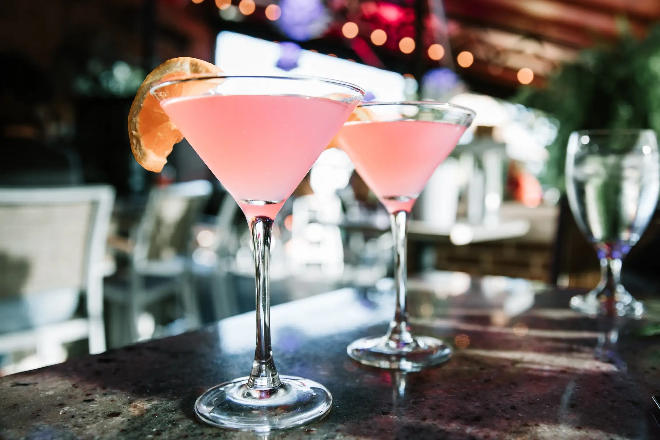 two glasses of pink liquid with a slice of orange on top of them