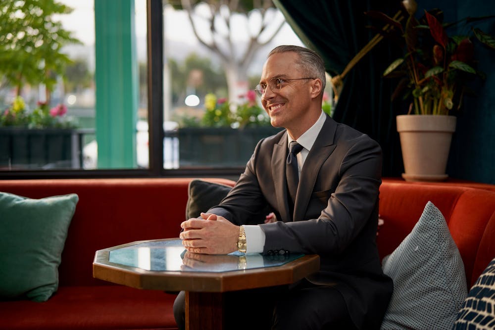 a man wearing a suit and tie sitting at a table