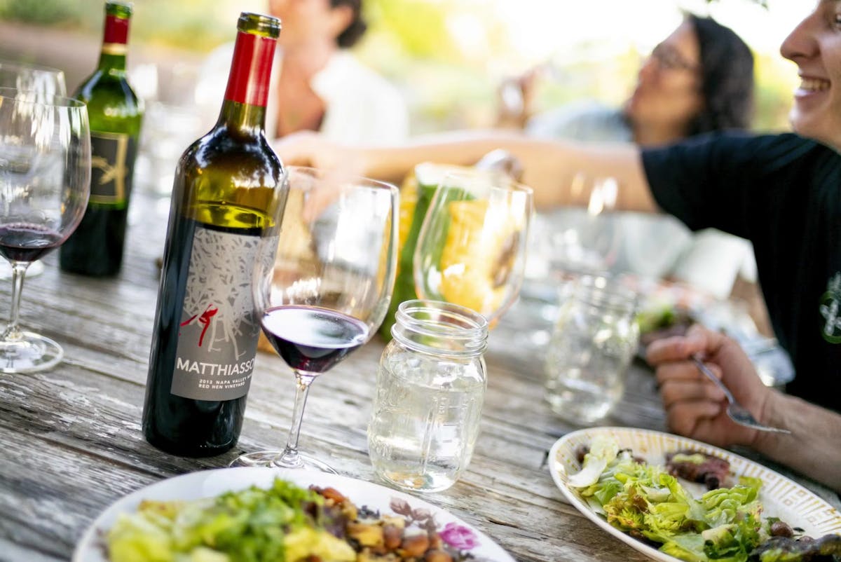 a person sitting at a table with food and a bottle of wine