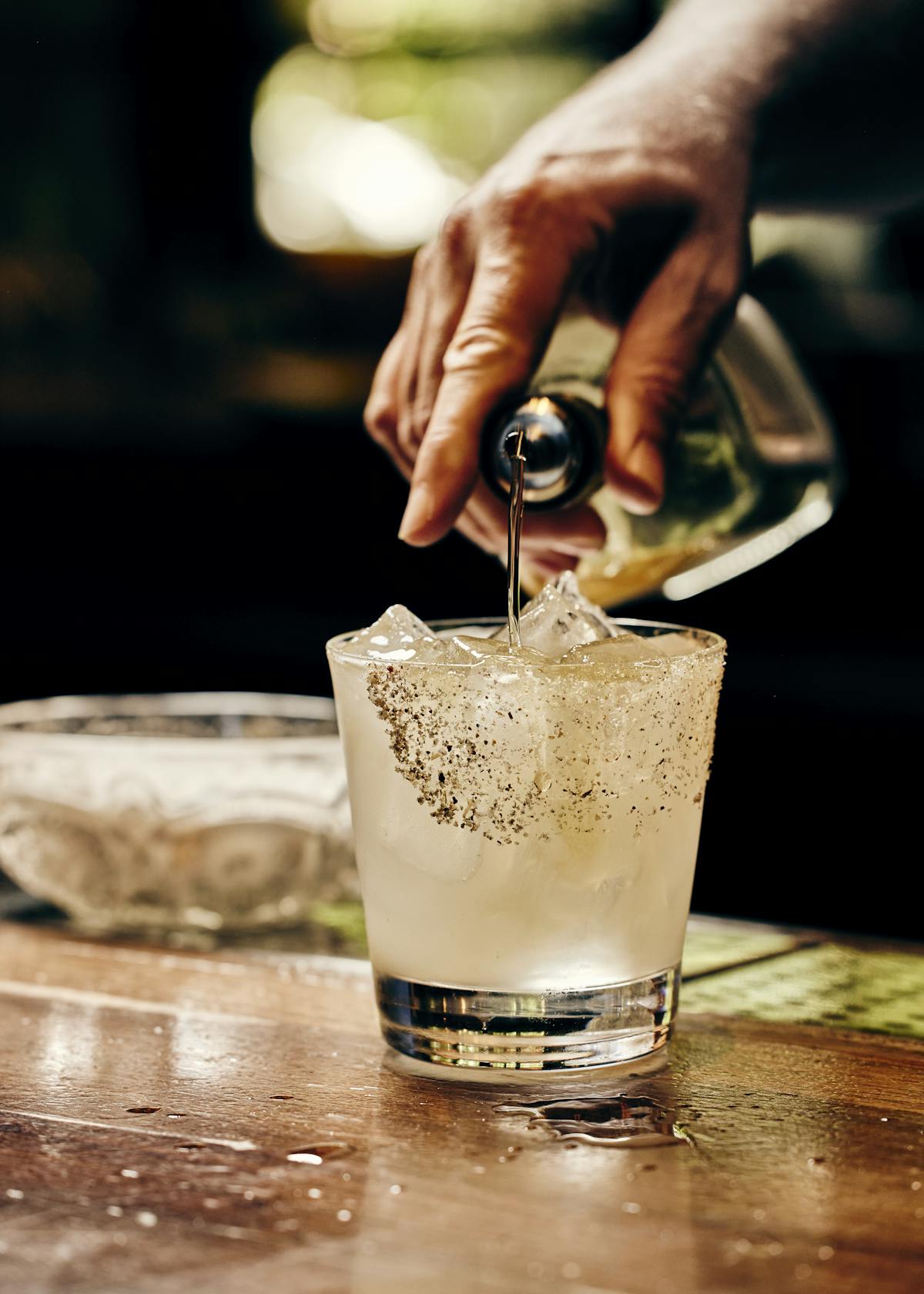 close up of a bartender pouring tequila into a margarita glass