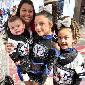 Alicia at her girls + baby at a cheer competition.