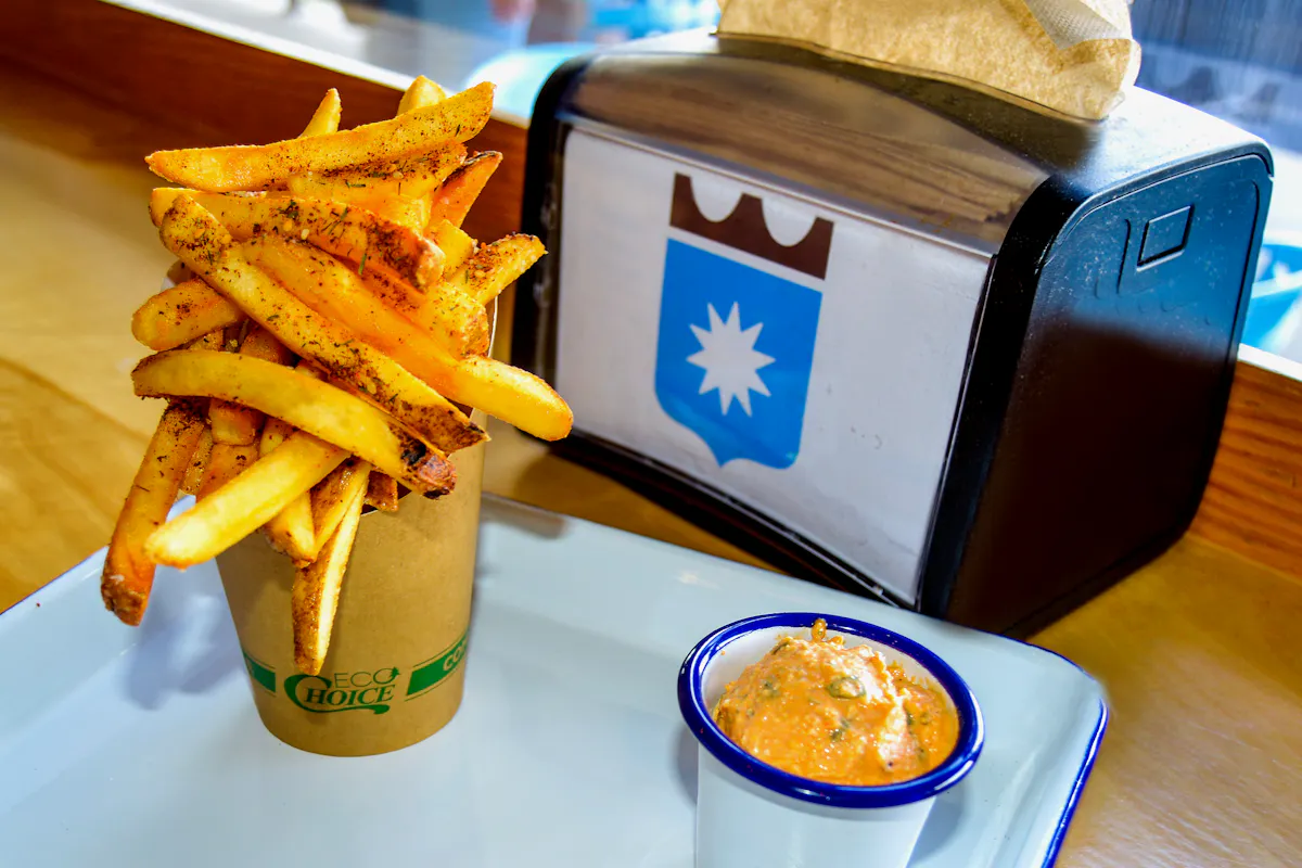 a closeup of some french fries next to a cup of salsa