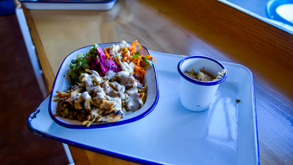 a plate of food filled with meat and greens salad next to it