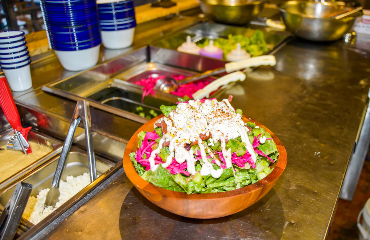 a wooden bowl filled with a greens salad