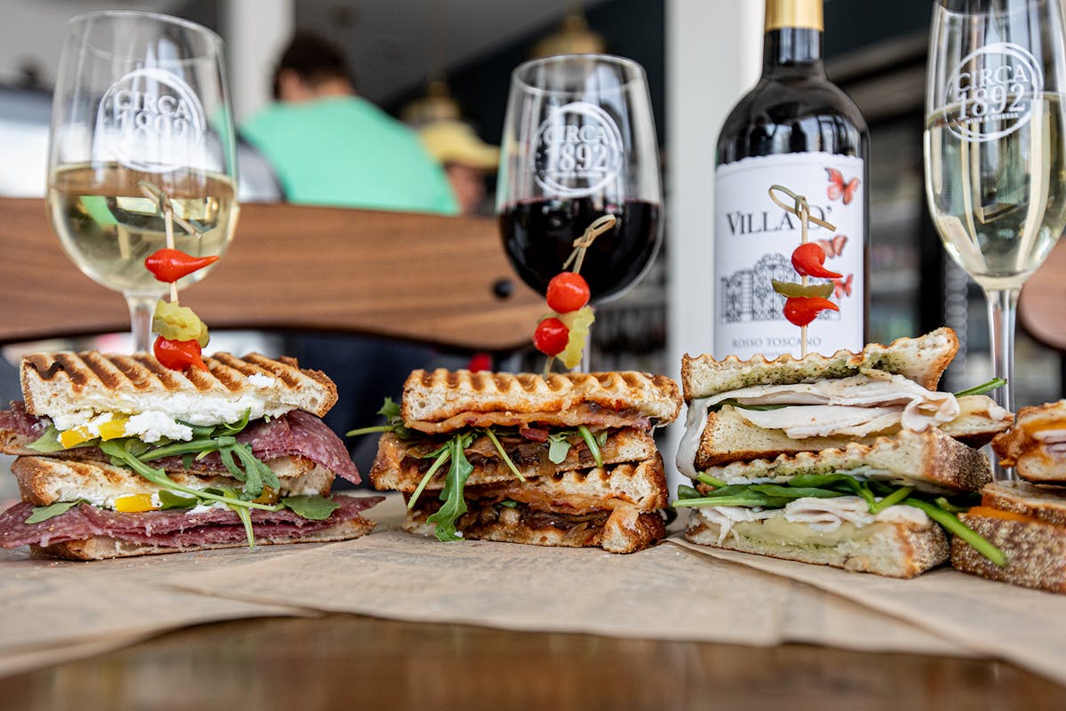 a close up of a bottle of wine and a sandwich on a plate