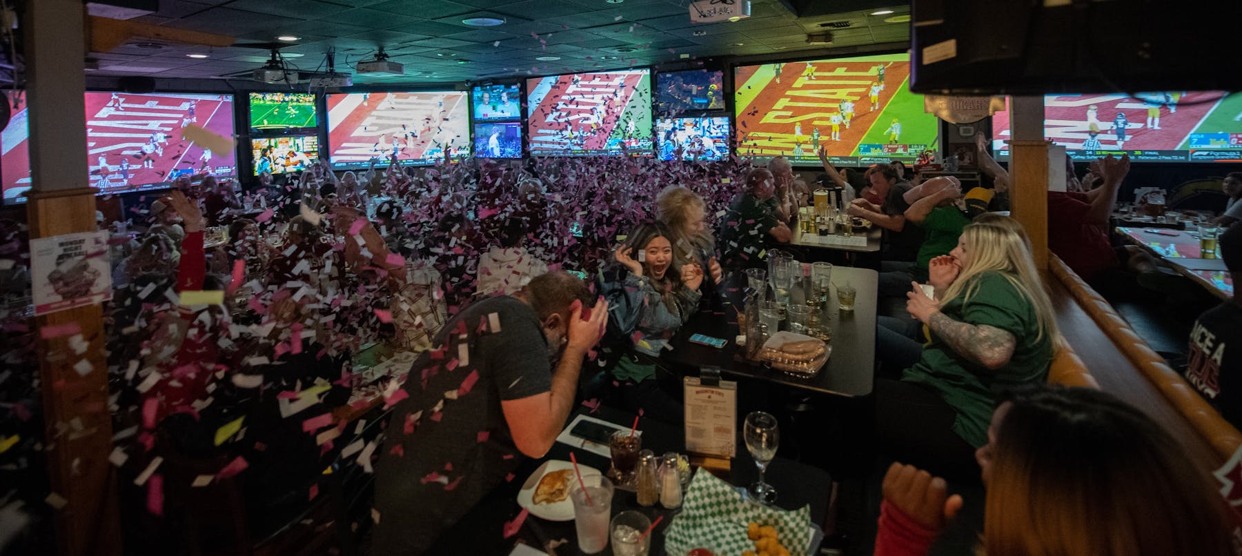 a group of people at the restaurant celebrating and throwing confetti