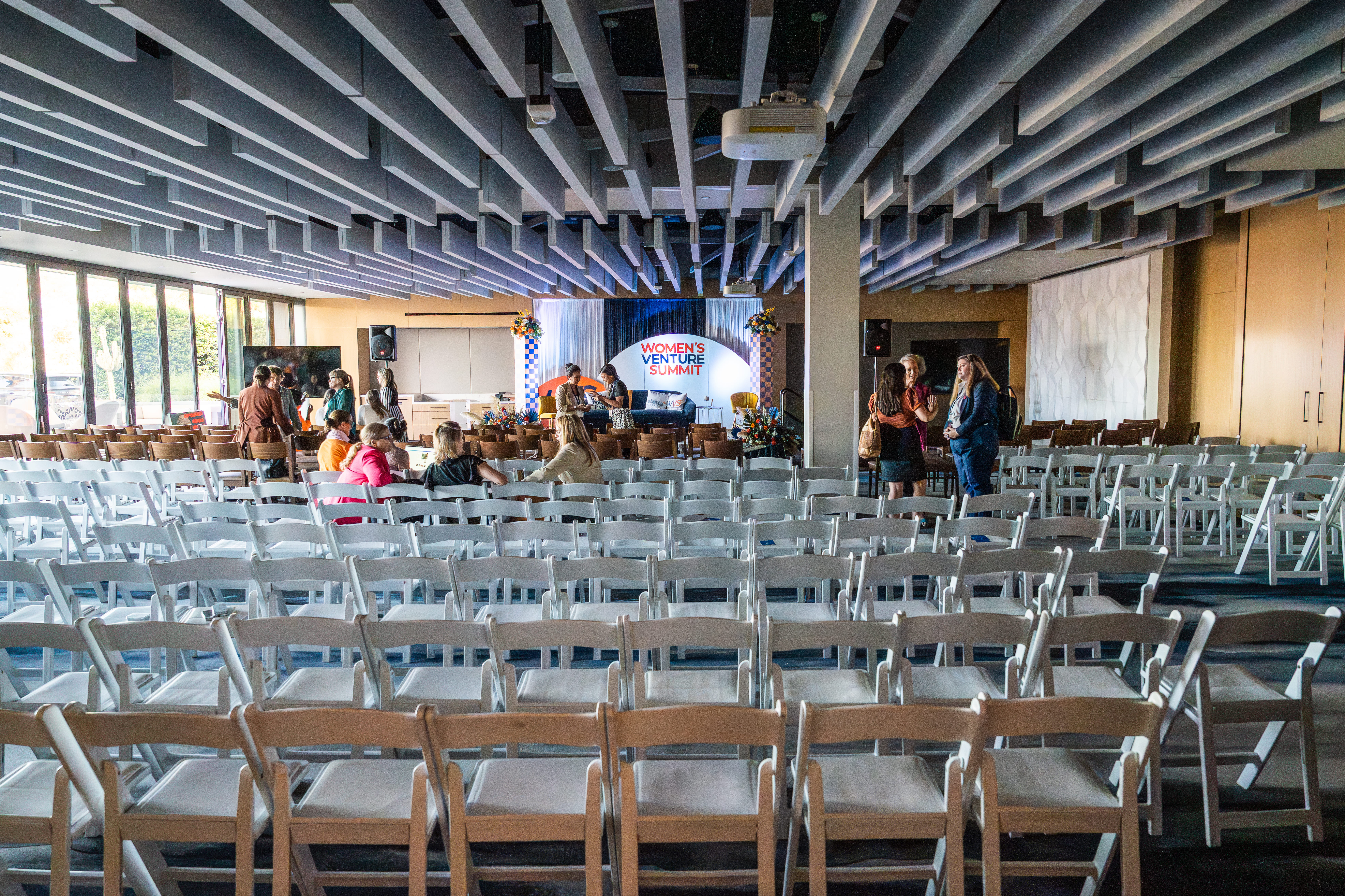 Rows of chairs facing a presentation stage in a covered event space at Joya Kitchen.
