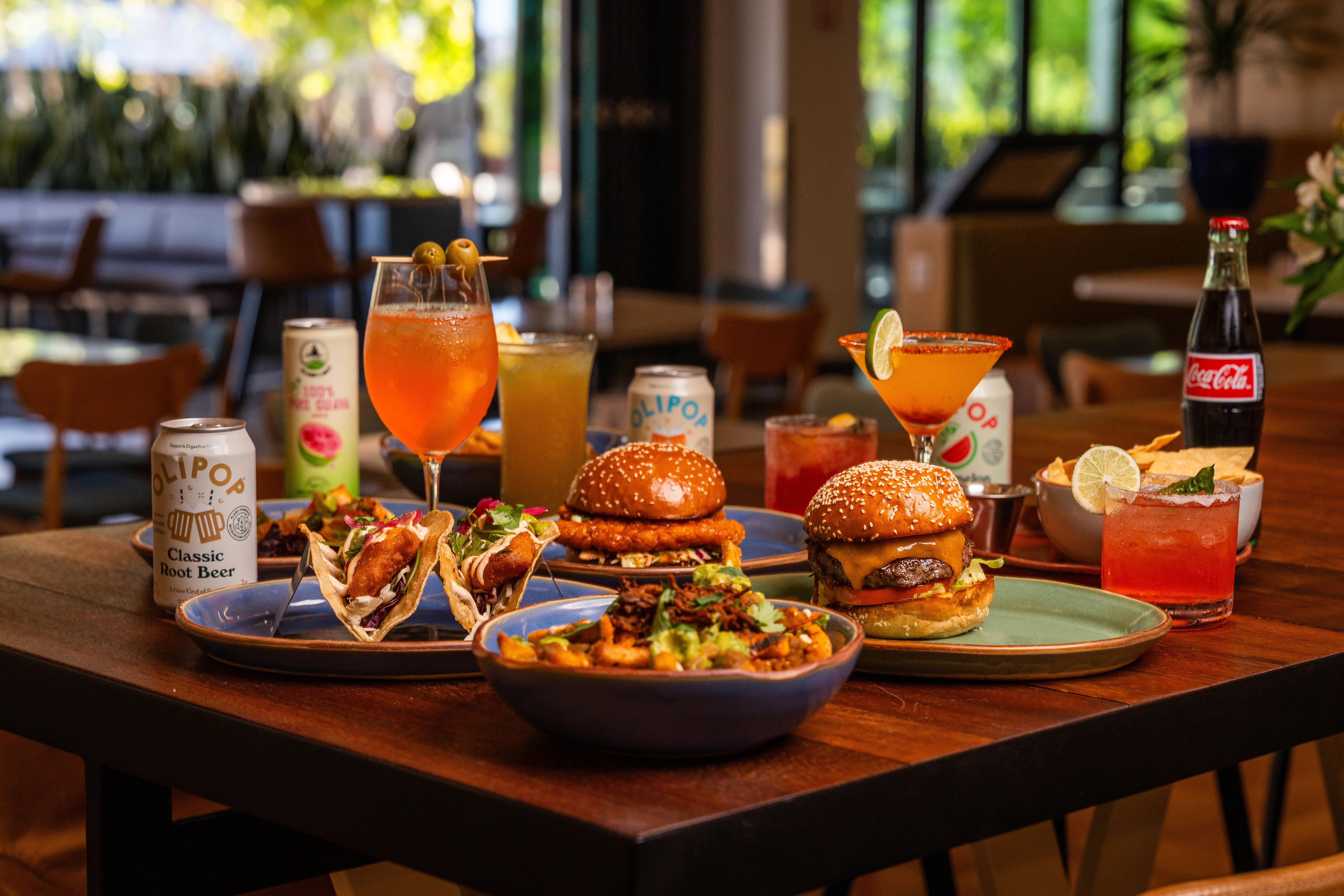 Burgers, tacos, fries and drinks arranged on a table at Joya Kitchen.