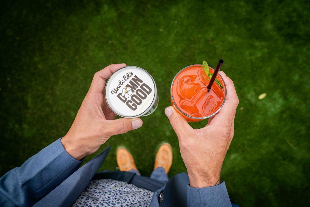 a man holding two drinks