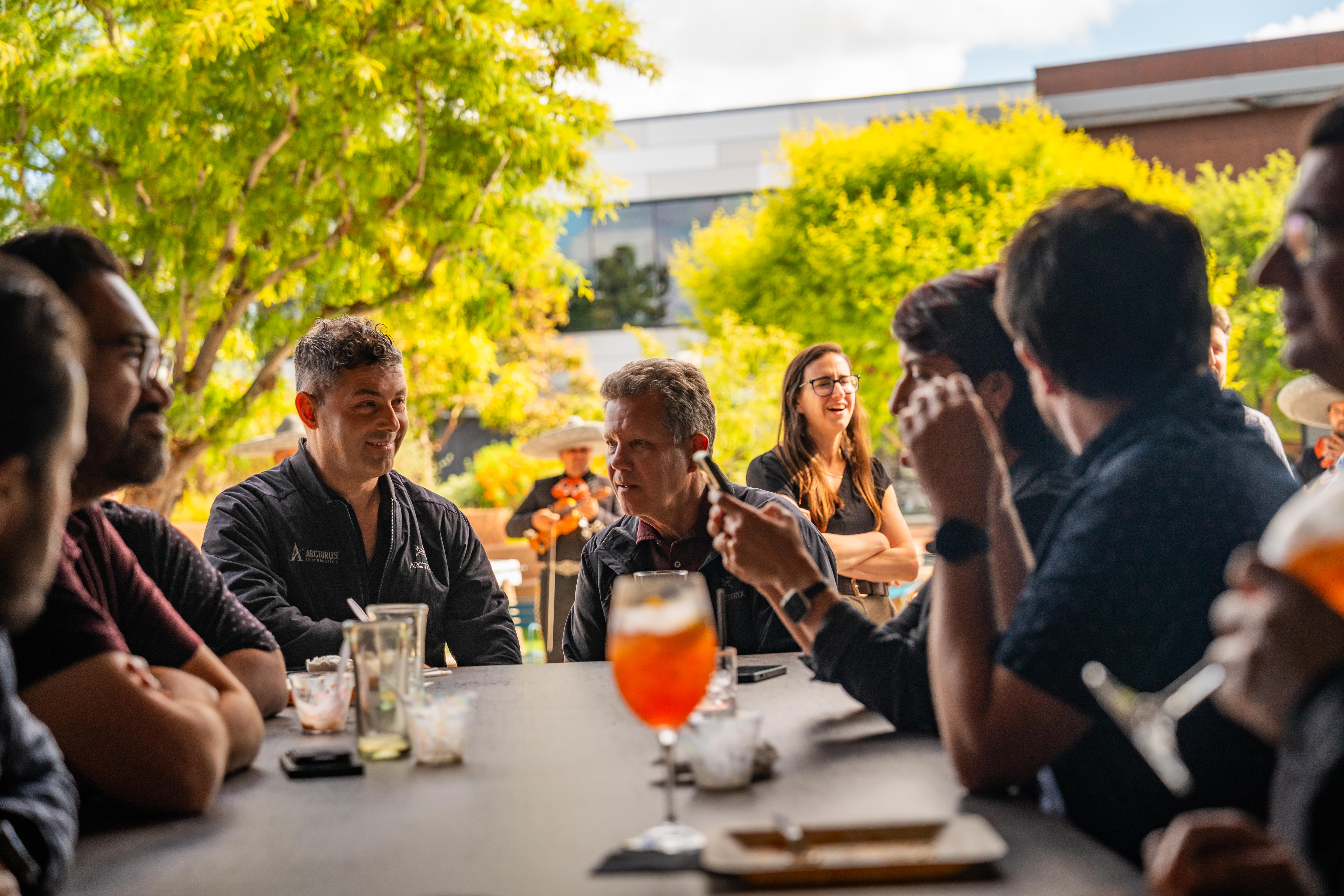 Guests sharing food and drinks on the patio at a Joya Kitchen event.